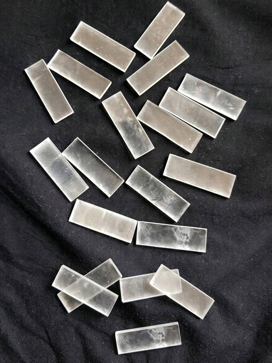 Several clear rectangular fire starter sticks scattered on a dark grey textured fabric background
