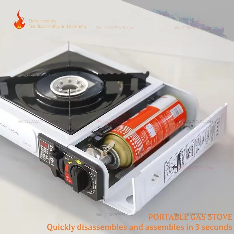 White portable gas stove with side compartment open, showing a red gas canister being loaded horizontally