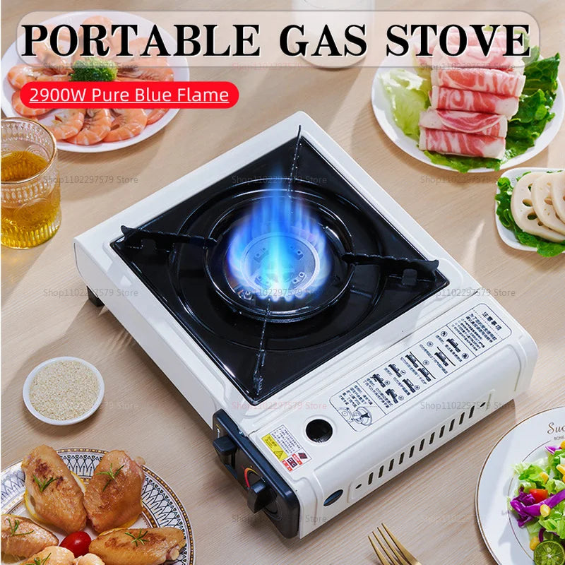 White portable gas stove with a black cooking grate and a bright blue flame, surrounded by plates of food